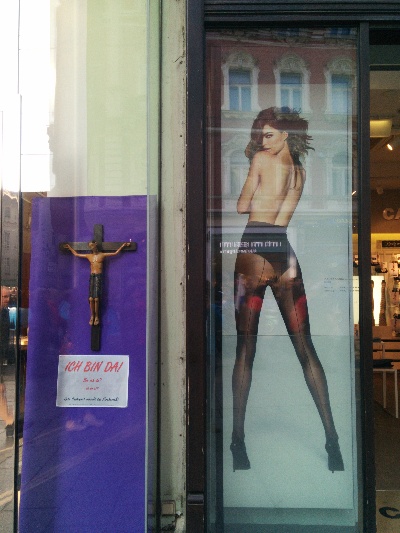 Jesus am Kreuz neben einem gewagten Strumpfhosenplakat